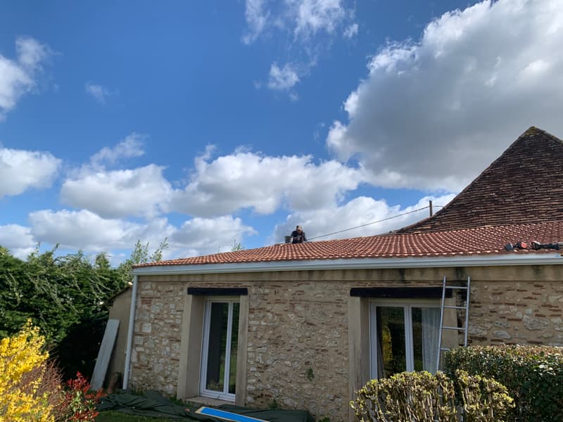 Artisan couvreur de TLP Rénove au travail sur la toiture d'une maison en pierre près de Sarlat
