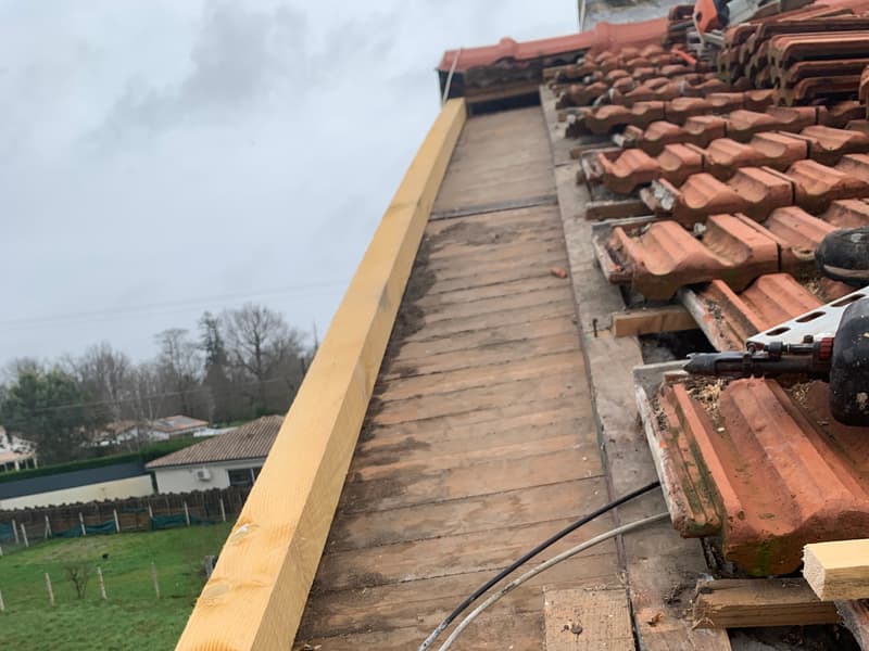 Pose d'une panne en bois neuve sur un voligeage ancien lors d'une réparation de charpente en Périgord
